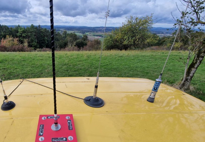 Mini-Magnator mit Antenne auf gelbem Autodach, im Hintergrund das Haßberge-Panorama